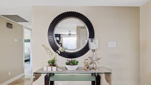Un meuble-lavabo pour la salle de bain avec un miroir rond, un plateau en verre et des objets décoratifs, notamment une étoile de mer et une plante en pot.