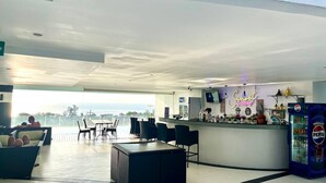 Un área de bar moderna con mostrador, asientos y vista al océano.
