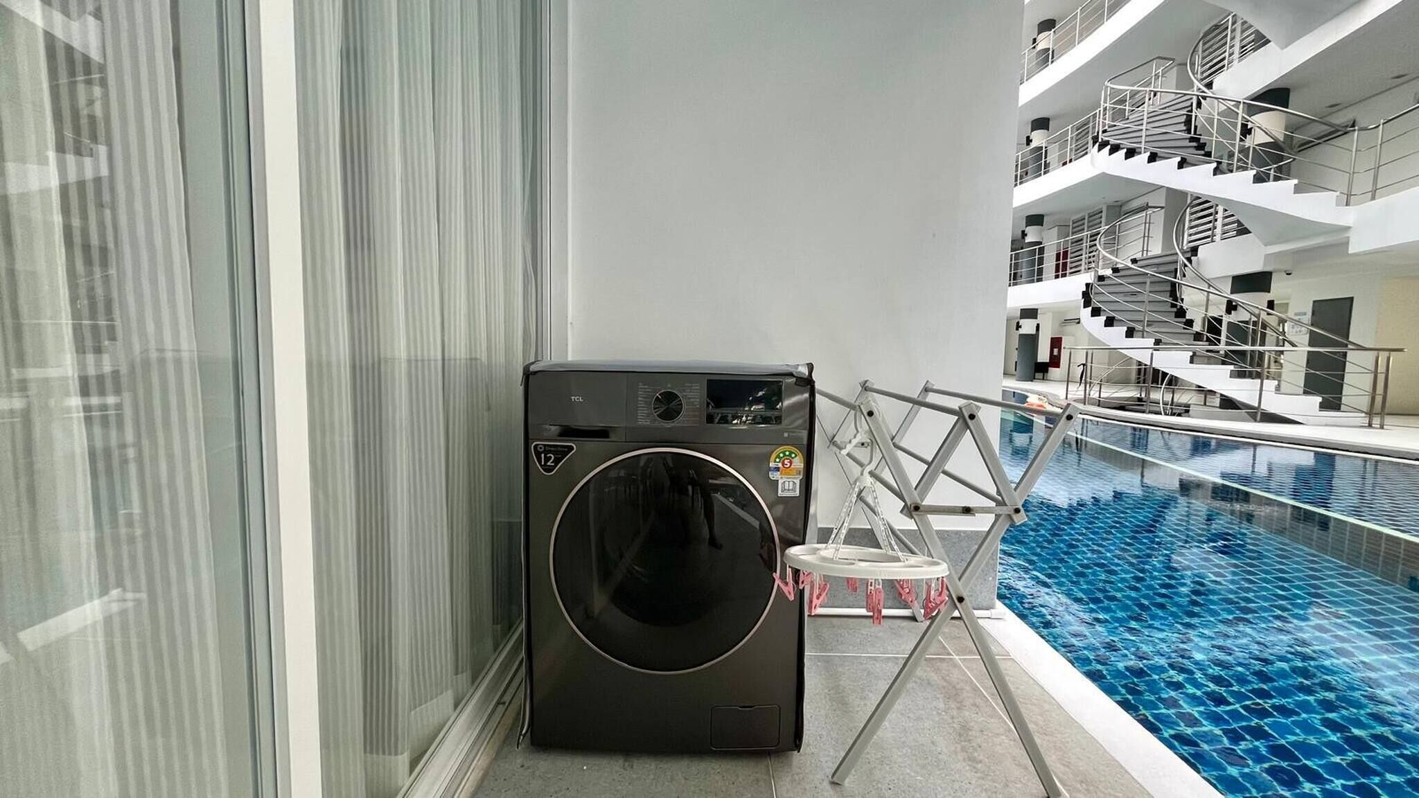 Een moderne hotelkamer met een ingebouwde wasmachine en droger, een zwembad en een trap naar een verdieping erboven.