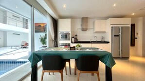 Una cocina moderna con armarios blancos, un refrigerador de acero inoxidable y un comedor con una mesa preparada para dos.