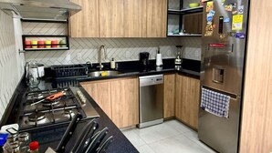Eine moderne Küche mit Holzschränken, einem Edelstahlkühlschrank und einem Geschirrspüler.