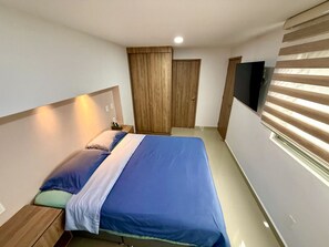 A bedroom with a bed, nightstands, a wardrobe, and a TV.