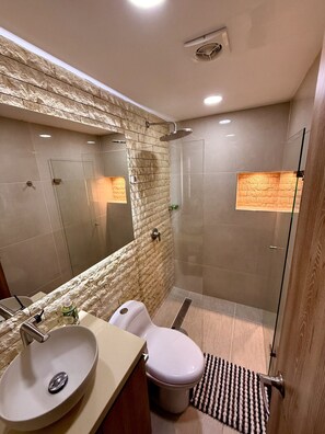 A modern bathroom with a large mirror, a sink, a toilet, and a shower area.