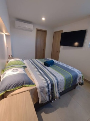 Ein Schlafzimmer mit zwei Betten, einem an der Wand montierten Flachbildfernseher und einer Decken-Klimaanlage.