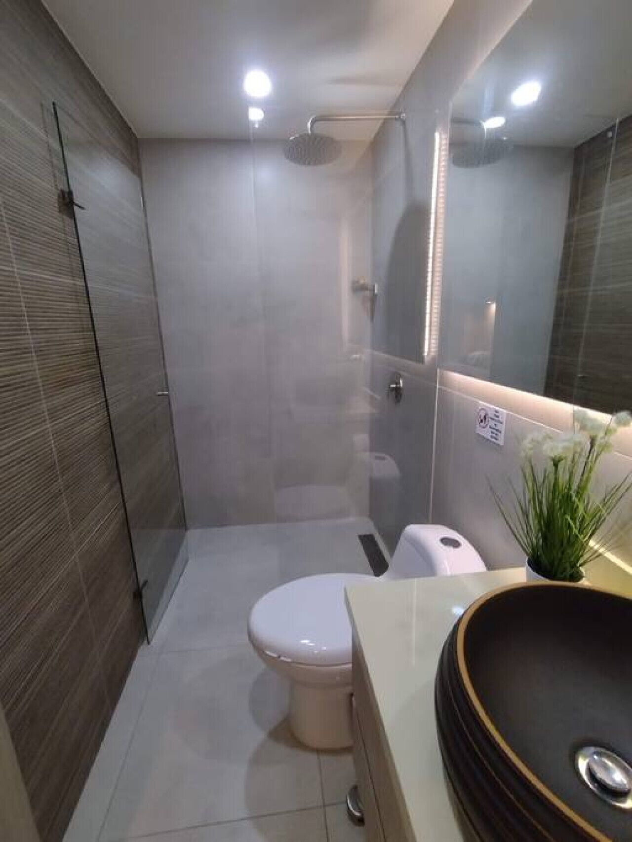 Une salle de bain moderne avec une douche à parois de verre, des toilettes et un lavabo doté d’un bac rond.