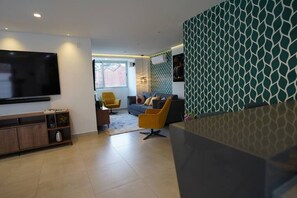Ein modernes Wohnzimmer mit einem Flachbildfernseher, einem Sofa, einem gelben Sessel und einer Wand mit Muster.