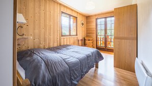 A wooden-paneled bedroom with a bed, a window, and a door leading to a balcony.