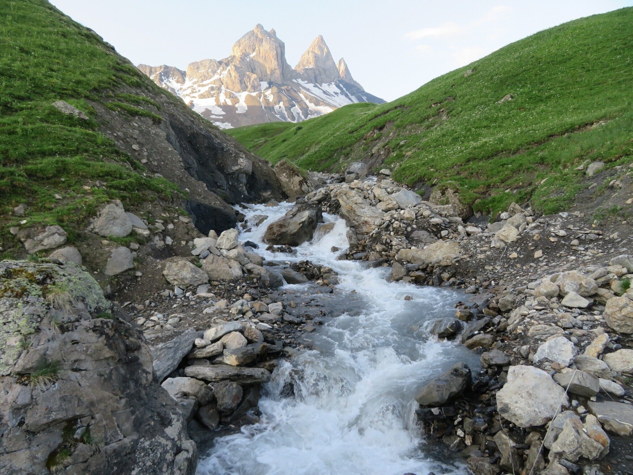 Un ruisseau aux rives rocheuses, avec une chaîne de montagnes en arrière-plan.