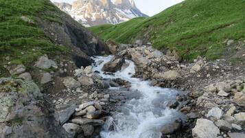Un ruisseau aux rives rocheuses, avec une chaîne de montagnes en arrière-plan.
