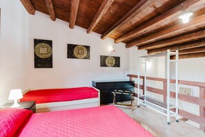 A bedroom with a wooden ceiling, two beds with red bedding, a desk, and a ladder. - Villa Loft 'Antico Baglio' – Scopello – Mountain View, Wi-Fi, Air Conditioning (Castellammare del Golfo)