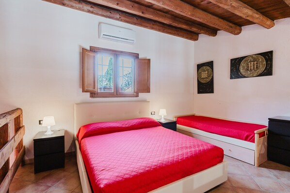 A bedroom with two beds, a window, and a wall-mounted air conditioner. - Villa Loft 'Antico Baglio' – Scopello – Mountain View, Wi-Fi, Air Conditioning (Castellammare del Golfo)