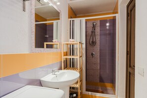 A bathroom with a sink, mirror, shower, and tiled walls. - Villa Loft 'Antico Baglio' – Scopello – Mountain View, Wi-Fi, Air Conditioning (Castellammare del Golfo)