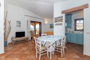 Un espace repas comprenant une table, des chaises et un téléviseur posé sur un meuble.