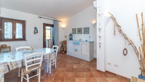 A dining area with a table, chairs, a cabinet, and decorative wall elements. - Apartment 'Casa Lauretta' with Sea View, Shared Pool and Air Conditioning (Porto Pollo)