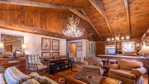 A rustic interior with wooden beams, a chandelier, and a cozy seating area with a fireplace.
