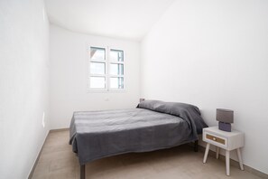 Une chambre à coucher avec un lit, une table de chevet, une lampe et une fenêtre.