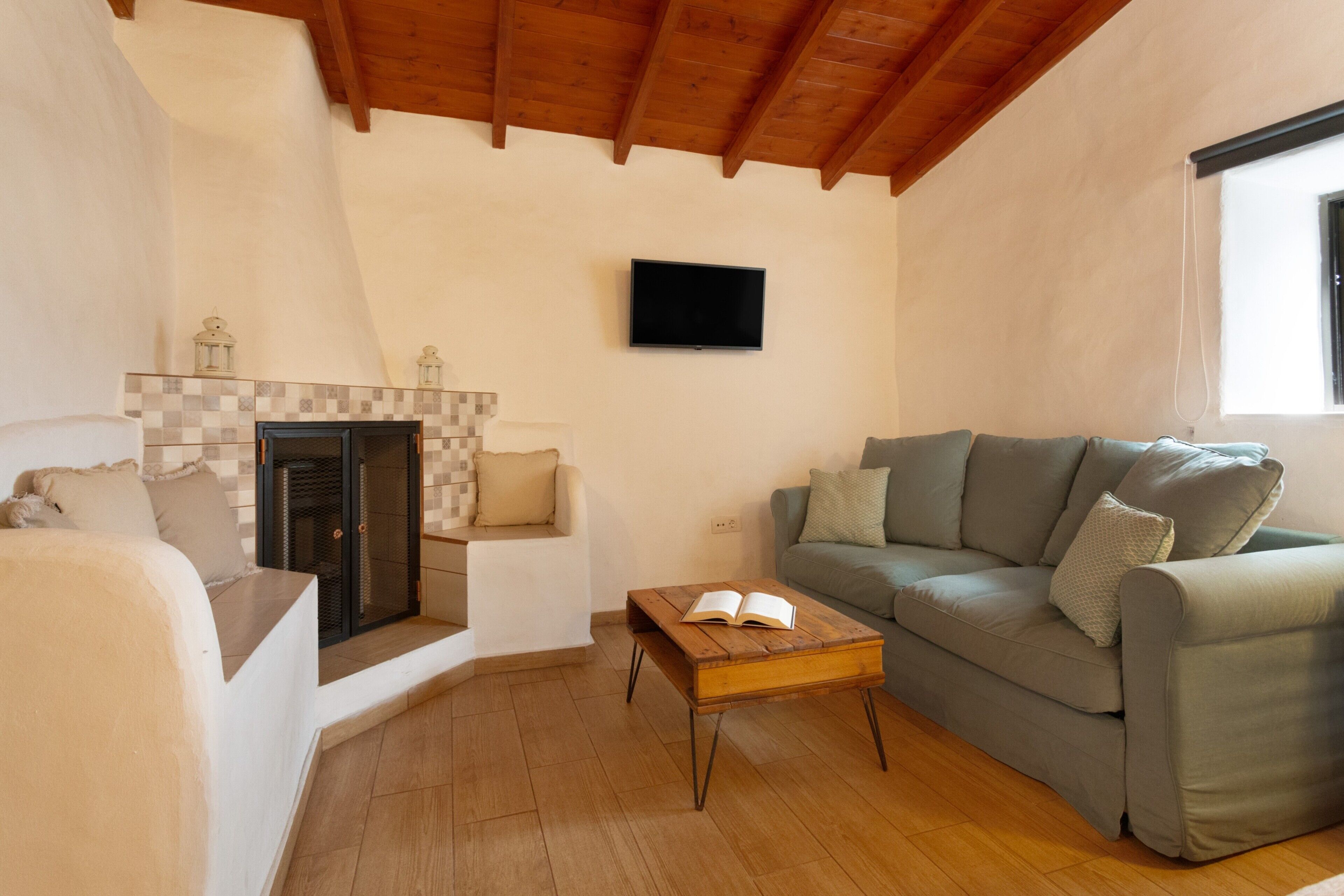 A living room with a fireplace, a sofa, a coffee table, and a television mounted on the wall.