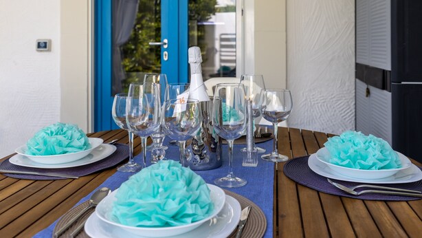 Ein Tisch, gedeckt mit mehreren Gläsern, einer Flasche und Tellern, mit einem blauen Mittelstück.