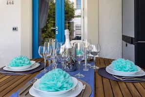 A table set with multiple glasses, a bottle, and plates with a blue centerpiece. - Apartment 'D R Holiday Home' with Private Garden close to the sea (Santa Maria del Focallo)