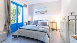Ein Schlafzimmer mit Bett, Nachttisch, Vorhängen am Fenster und einem Bild an der Wand.