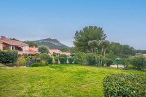 A residential area with houses, a grassy lawn, and a hill in the background. - Apartment 'Grande Terrasse Vue Mer' with Sea View, Shared Pool and Wi-Fi (Saint-Raphaël)