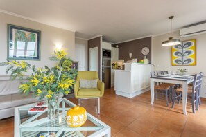A living room with a sofa, a glass coffee table, a yellow chair, and a dining area with a table and chairs. - Apartment 'Grande Terrasse Vue Mer' with Sea View, Shared Pool and Wi-Fi (Saint-Raphaël)