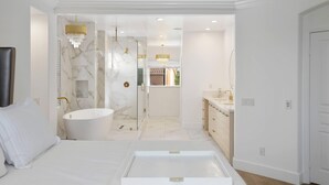 Un baño moderno con una bañera independiente, un tocador con espejo y una araña.