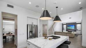 Una cocina moderna con una isla central, electrodomésticos de acero inoxidable e iluminación colgante.