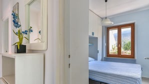 Ein Schlafzimmer mit Bett, Fenster mit Aussicht, Nachttisch und Spiegel.