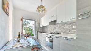 Eine moderne Küche mit weißen Schränken, einer gefliesten Spritzschutzwand und einem Essbereich mit Tisch für zwei Personen.