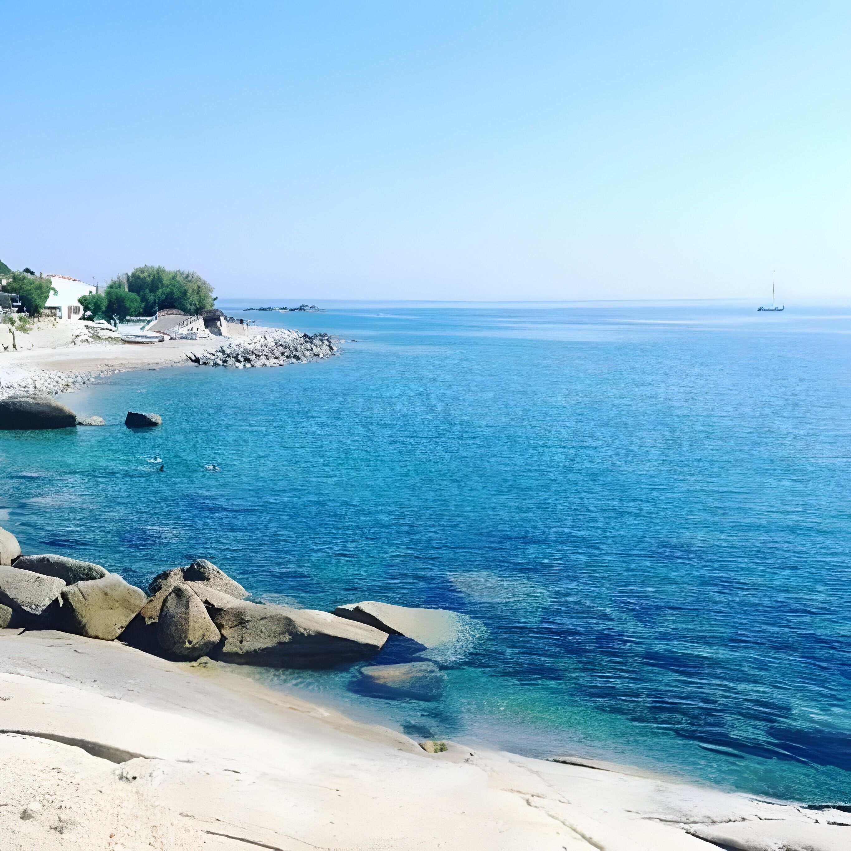 Uma praia costeira com águas azuis cristalinas, margem rochosa e um veleiro ao longe.