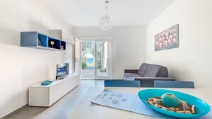 Ein modernes Wohnzimmer mit Fernseher, Sofa und Esstisch mit dekorativer Schale.