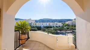 A balcony with a view of a town, a potted plant, and a ladder. - Apartment '1' with Mountain View, Wi-Fi and Air Conditioning (Karpathos Town)