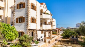 A multi-story building with balconies, a stone facade, and outdoor seating areas. - Studio Apartment 'No 2' with Mountain View, Wi-Fi and Air Conditioning (Karpathos Town)