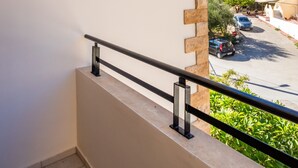 A balcony with a railing, a sign reading 'PETRA,' and a view of a parking area and greenery. - Studio Apartment 'No 2' with Mountain View, Wi-Fi and Air Conditioning (Karpathos Town)