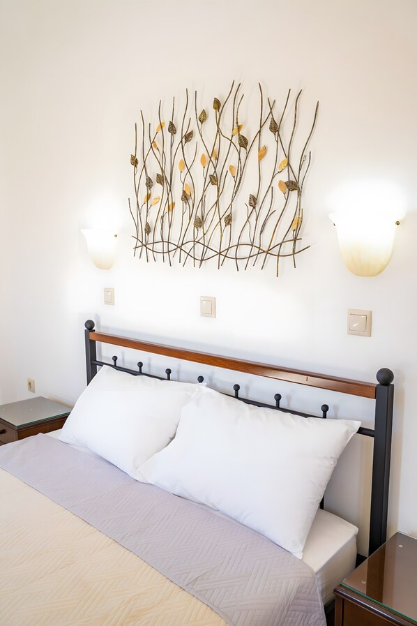 A neatly made bed with a wooden headboard, white pillows, and a light-colored bedspread.