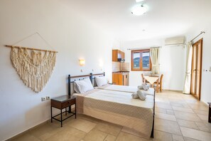 Ein Schlafzimmer mit zwei Betten, einem Nachttisch, einer Wanddekoration, einem Fenster mit Vorhängen und Blick ins Freie.