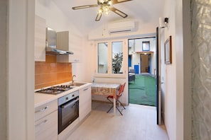 A compact kitchen with a gas stove, oven, and a ceiling fan.