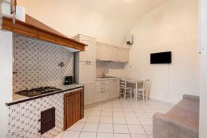 A compact kitchen with a gas stove, a sink, and a dining area with a table and chairs.