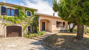 A stone-paved driveway leading to a house with a tiled roof, a wooden door, and a large tree in the foreground. - Holiday Home 'La Provençale' with Private Pool, Private Terrace and Wi-Fi (Châteaurenard)