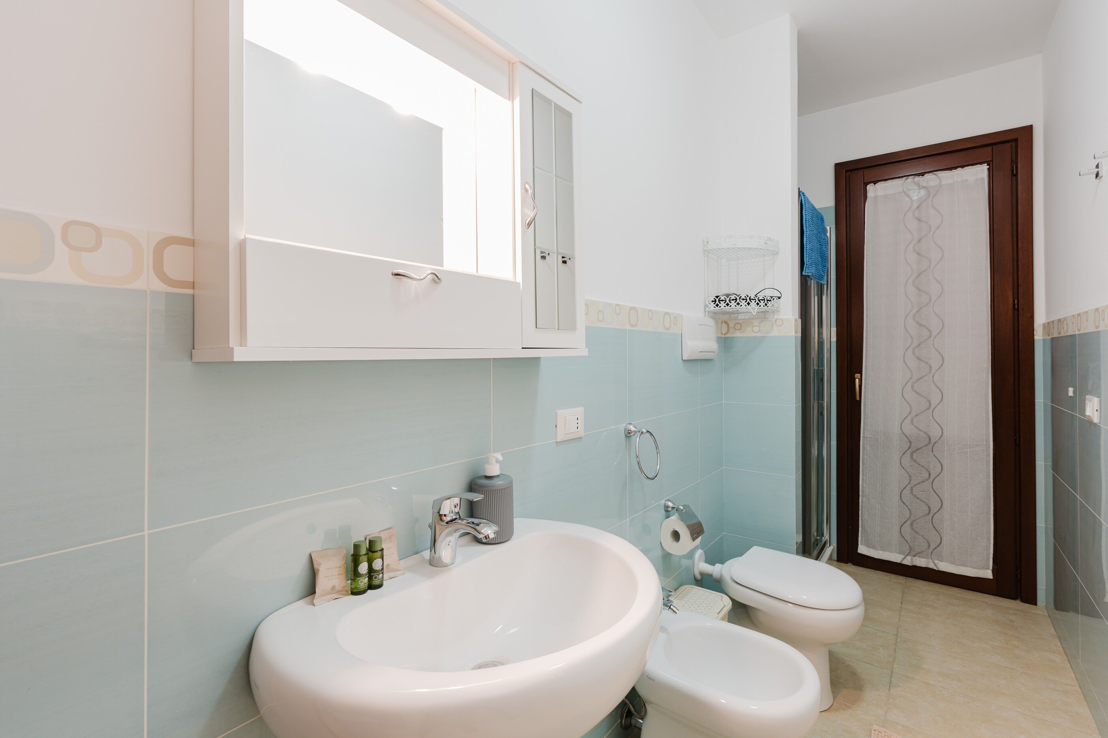 Ein Badezimmer mit einem großen Waschbecken, einer Toilette, einem Spiegel und einer Duschkabine.