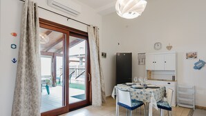 A dining area with a table set for four, a refrigerator, and a sliding glass door leading to an outdoor area.