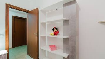 A room with a wooden door, white shelving unit, and a pink basket.