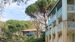 A multi-story building with balconies, a grassy lawn, and a large tree. - Cozy Studio in Moliets et Maa with Private Terrace, Barbecue, Ideal for 4 Guests (Moliets et maa)