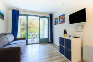 Et moderne værelse med sofa, TV, skab og en skydedør til et udendørs område.