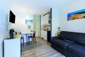 En kompakt bolig med et tekøkken, spiseplads og sofa.