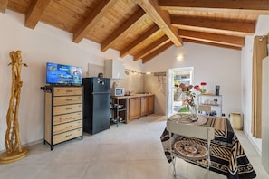 A spacious kitchen with wooden beams, a built-in TV, and a dining area with a patterned tablecloth. - Apartment 'Nature E Relax' with Mountain View, Private Terrace and Wi-Fi (Osiglia)