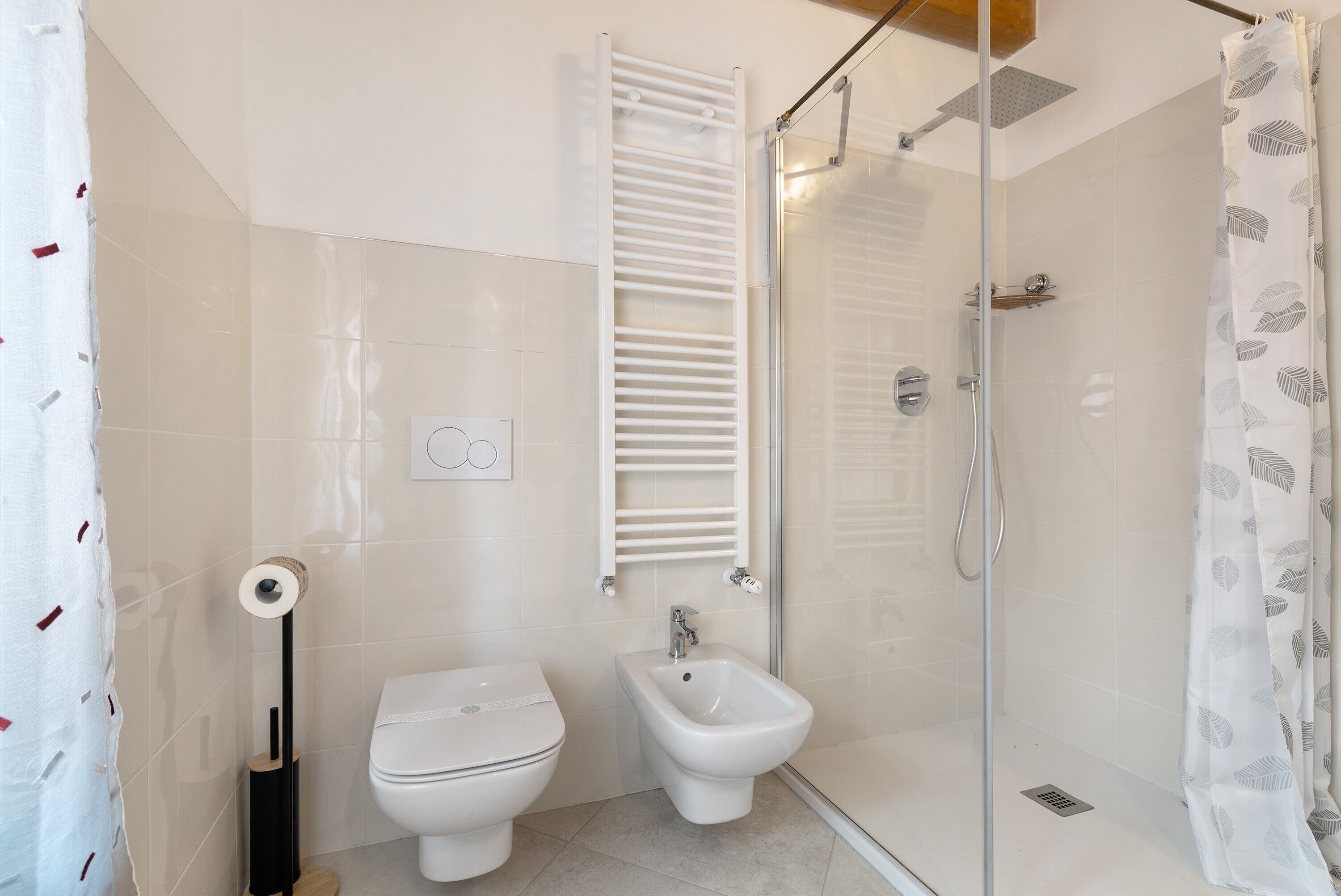 Une salle de bain équipée de toilettes, d’un bidet et d’une douche à parois de verre.