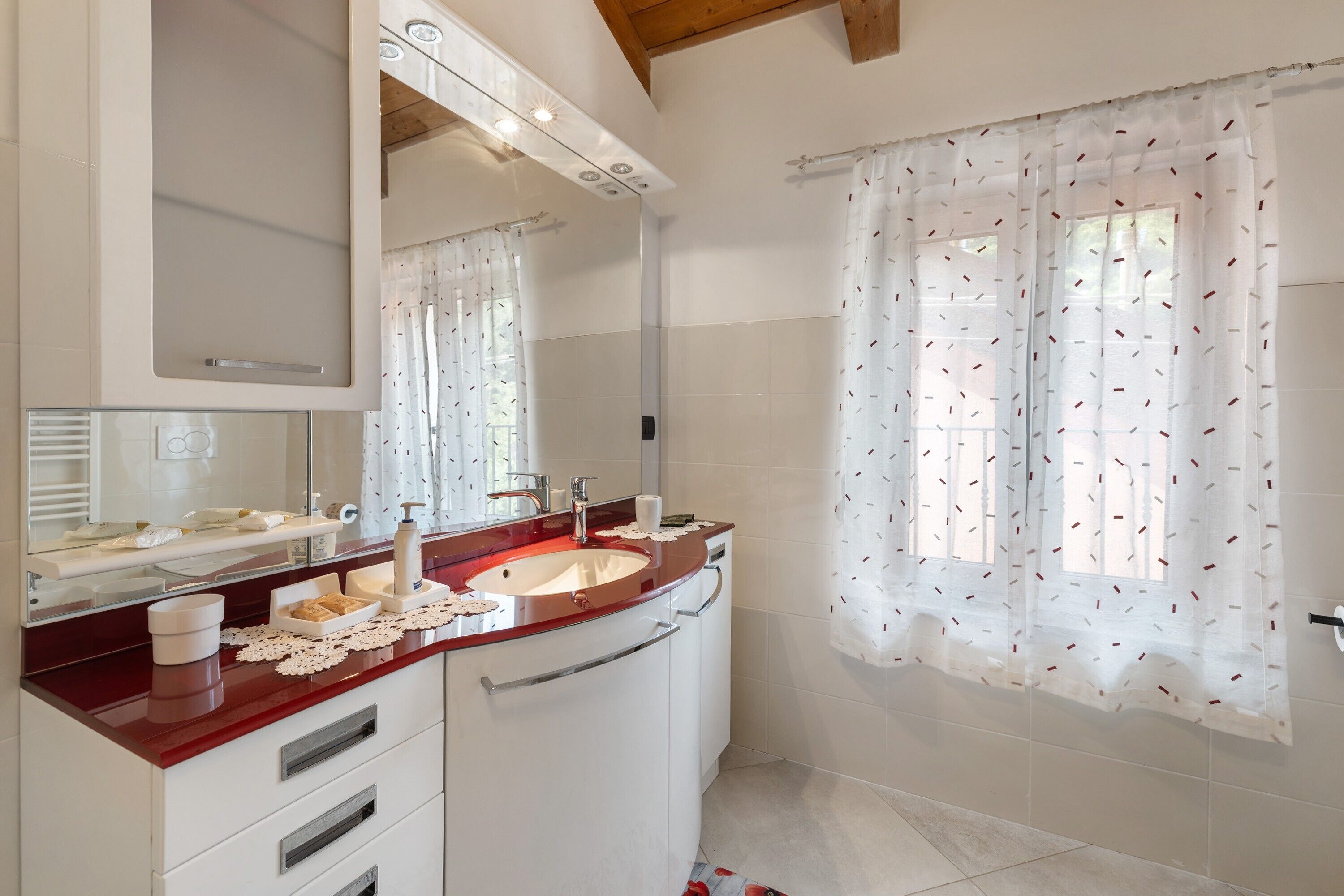 A bathroom with a vanity, sink, mirror, and shower curtain.