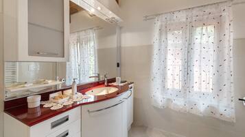A bathroom with a vanity, sink, mirror, and shower curtain.